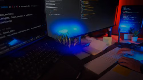Programmer coding at a desk with several monitors