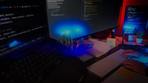 Programmer coding at a desk with several monitors