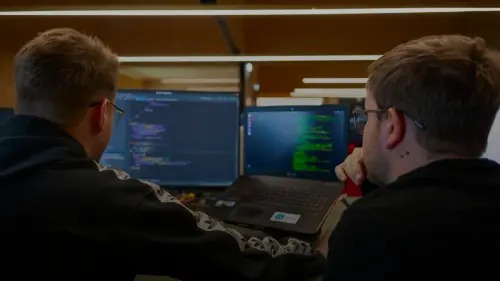 two men sitting in front of a laptop computer