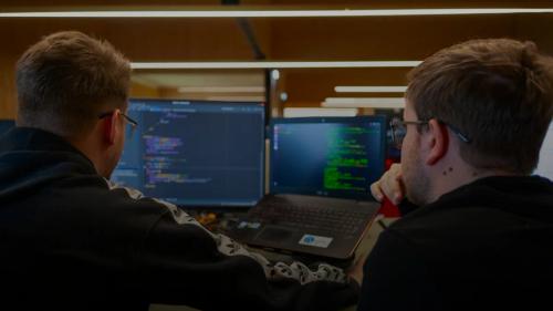 two men sitting in front of a laptop computer