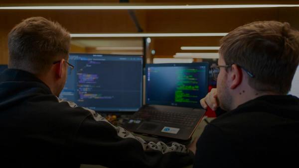 two men sitting in front of a laptop computer