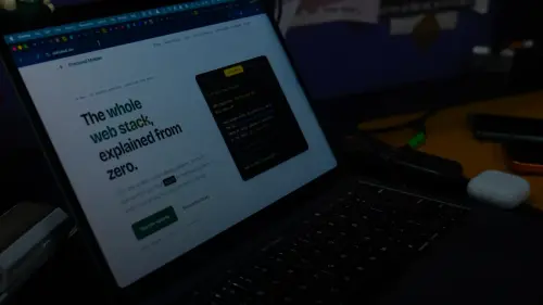 A laptop screen displaying a web development tutorial website on a dark desk
