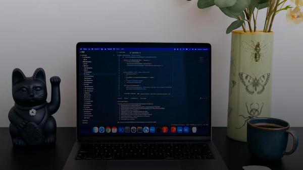 Laptop displaying code next to a lucky cat statue