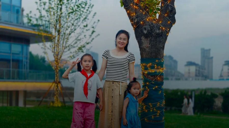 Mother and two daughters stand by a decorated tree