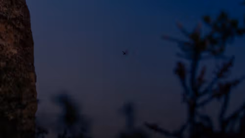 a small plane flying over a large rock