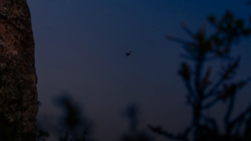 a small plane flying over a large rock