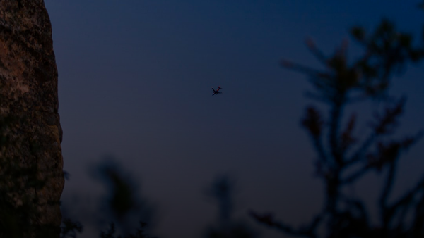 a small plane flying over a large rock