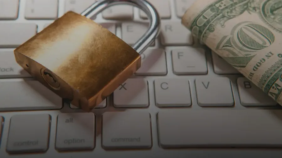 A padlock and dollar bills rest on a computer keyboard