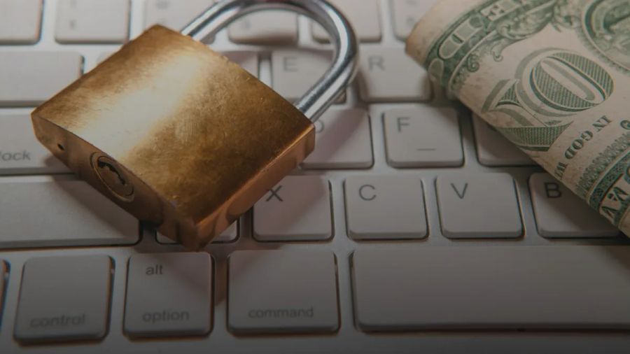 A padlock and dollar bills rest on a computer keyboard