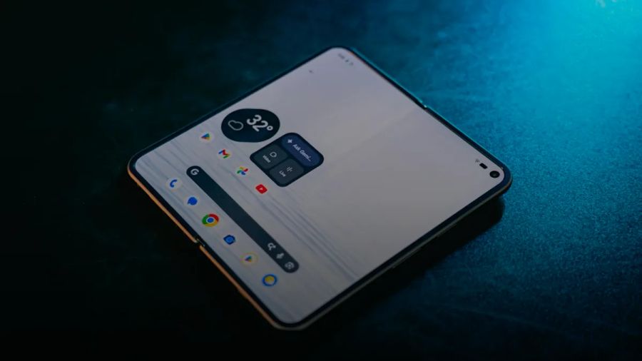 A foldable smartphone with an open screen displaying app icons on a dark surface