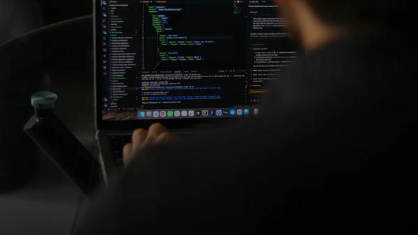 Developer typing code on a laptop screen.