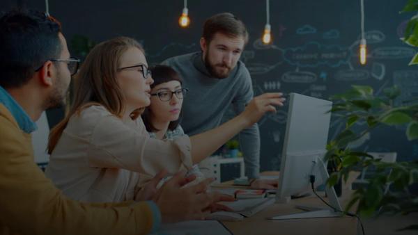 Team collaborating around a computer in an office.