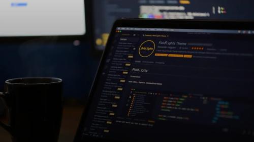 A laptop screen displaying code and a steaming mug on a desk