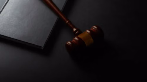 Wooden gavel resting on a dark surface next to book