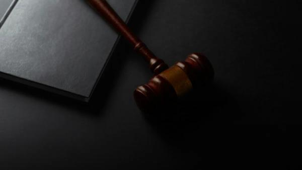 Wooden gavel resting on a dark surface next to book