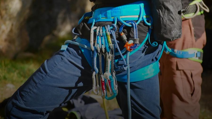 a man in a harness holding a bunch of tools