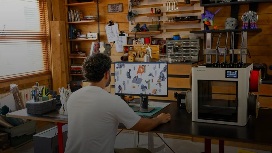Man working on computer in a workshop with 3D printer