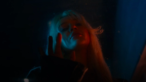 Woman with blonde hair illuminated by blue light