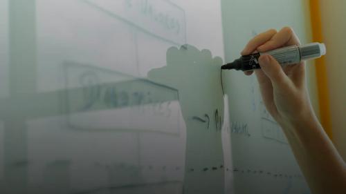 Hand drawing a diagram on a whiteboard.