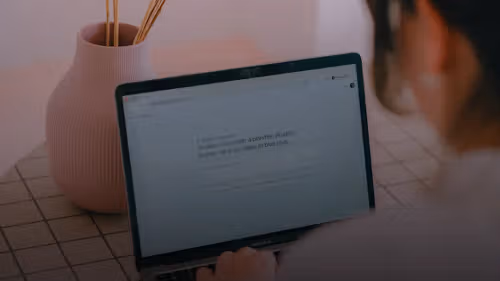 Woman typing on a laptop with a vase nearby