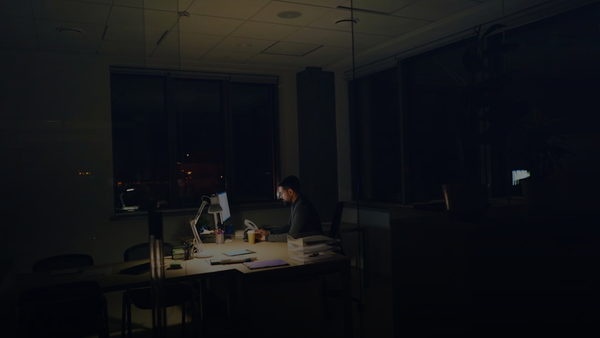 Man working late at a dimly lit office desk.