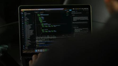 Person typing code on a laptop screen
