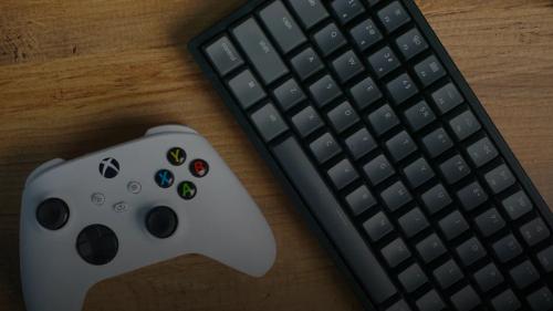 White xbox controller and a mechanical keyboard on wood