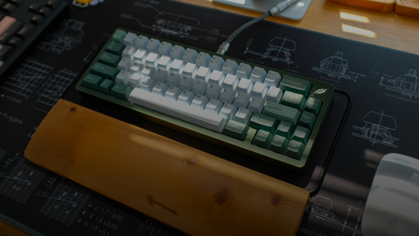 A mechanical keyboard sits on a desk mat.