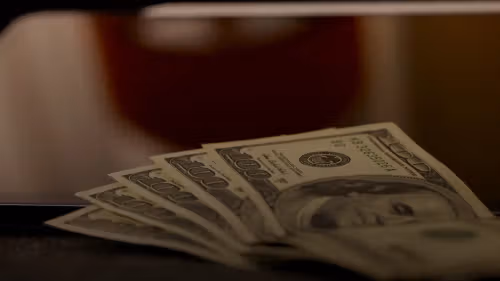 a stack of money sitting on top of a laptop computer