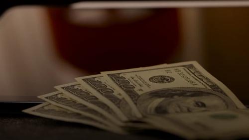 a stack of money sitting on top of a laptop computer