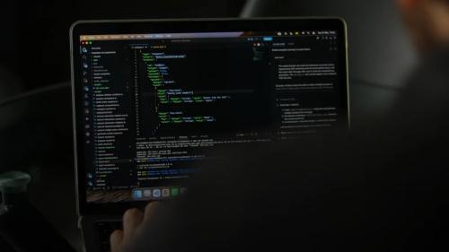 Person typing code on a laptop screen.