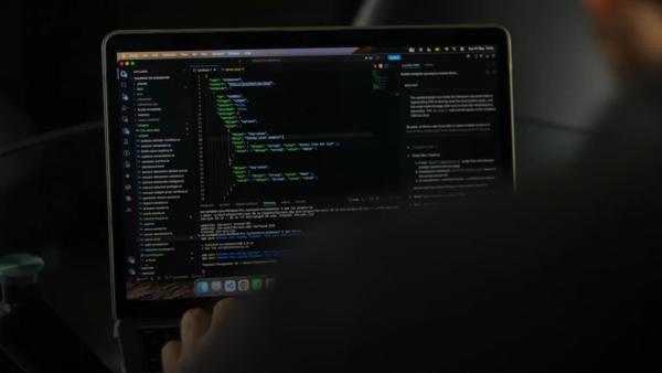 Person typing code on a laptop screen.