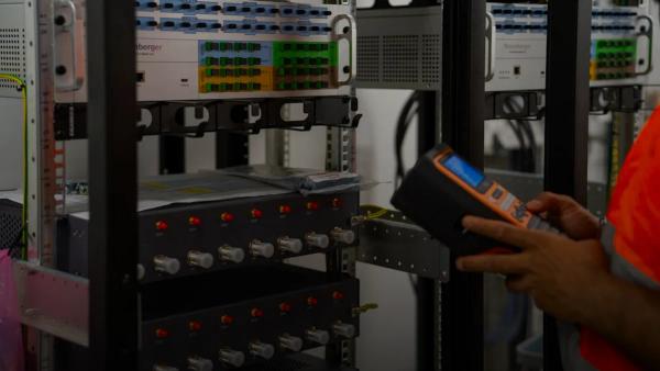 Technician inspecting server racks with a handheld diagnostic tool.