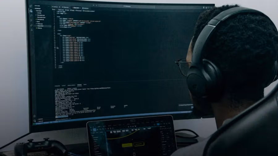 A man sitting in front of a computer wearing headphones
