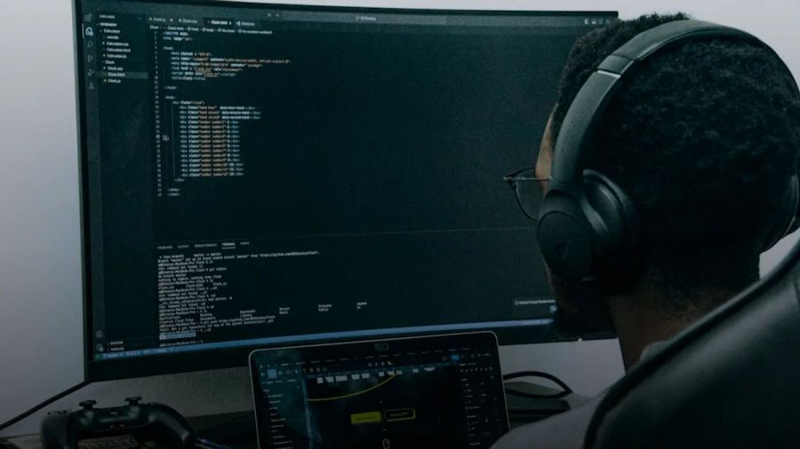 A man sitting in front of a computer wearing headphones