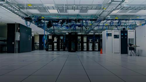 A server room with rows of black and white cabinets under blue cables