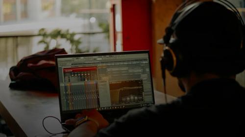 Person wearing headphones using laptop with audio software