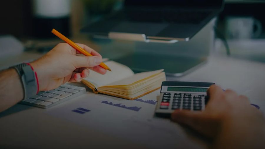 a person sitting at a desk with a calculator and a notebook