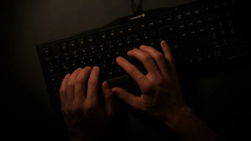 a person is typing on a black keyboard
