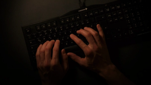 a person is typing on a black keyboard