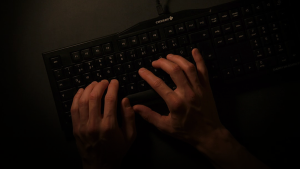 a person is typing on a black keyboard
